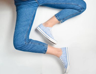 Kot pantolon ve spor ayakkabı beyaz bir arka plan üzerinde kadın bacaklar. Top Vie