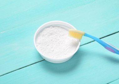 Diş tozu ve mavi ahşap bir masa üzerinde bir diş fırçası. Oral hijyen