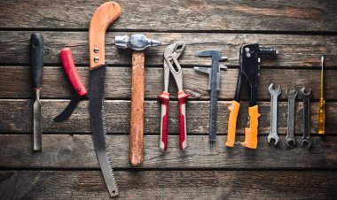 Ahşap bir masa üzerinde bir çalışma aracı. Testere, çekiç, tornavida, pense, dimes, bıçak, top vie