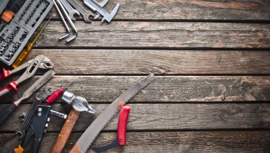 Ahşap bir masa üzerinde bir çalışma aracı. Testere, çekiç, tornavida, pense, dimes, bıçak, üstten görünüm, kopya girintili