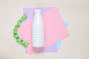 Yoğurt cetvel renkli kağıt arka plan, üstten görünüm üzerinde plastik şişe. Ağırlık kaybetme kavramı