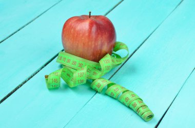 Bir cetvel mavi ahşap arka plan üzerinde sarılı Olgun kırmızı elma