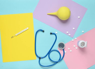 Tıbbi malzeme renkli kağıt arka plan üzerinde. Lavman, stetoskop, termometre, vitaminler şişe. Tıbbi kavramı. Top Vie