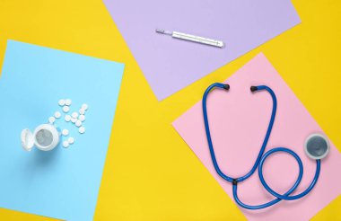 Tıbbi malzeme renkli kağıt arka plan üzerinde. Stetoskop, termometre, vitaminler şişe. Tıbbi kavramı. Top Vie