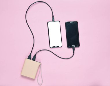 Pastel pembe bir arka plan üzerinde iki akıllı güç banka ücretleri. Modern araçlar. Üstten görünüm. Minimalis