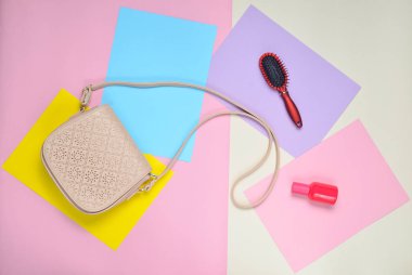 Deri çanta, tarak, pastel renkli bir arka plan üzerinde parfüm şişesi. Minimalizm. Top Vie