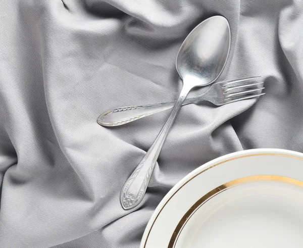 Kaşık, çatal, plaka üzerinde gri bir ipek masa örtüsü. Romantik bir akşam yemeği. Üstten görünüm