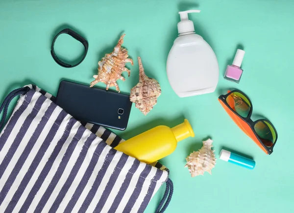 Plaj çantası ve aksesuarları pastel mavi arka plan üzerinde plaj düzendeki rahatlamak için. Deniz, yaz saati Resort'ta kavramı. Üstten görünüm, düz yatıyordu, minimalis