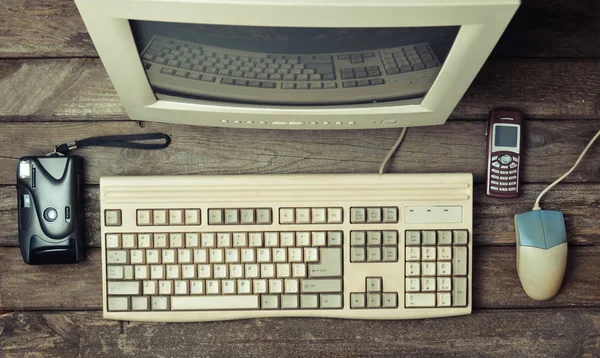 Retro stationary computer on a rustic wooden desk, vintage workspace. Monitor, keyboard, computer mouse, top view, flat la