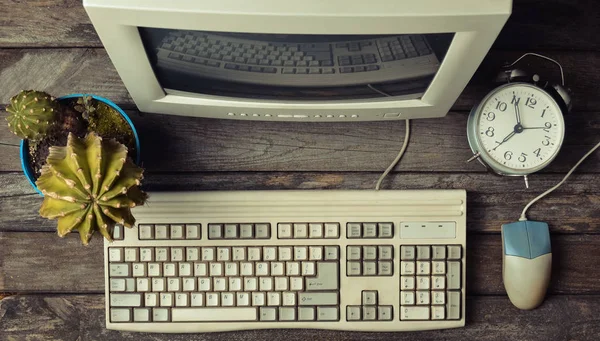 Retro stationary computer on a rustic wooden desk, vintage workspace. Monitor, keyboard, computer mouse, top view, flat la