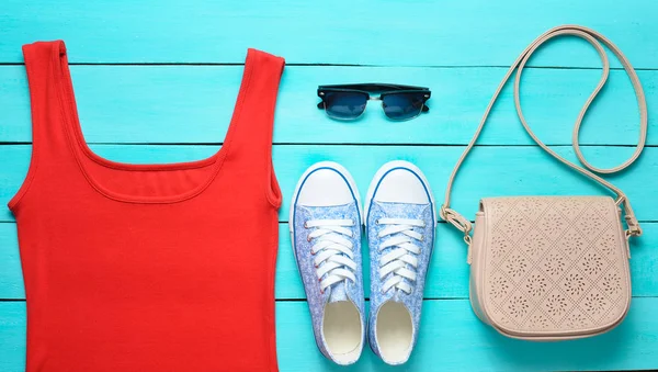 Röd Shirt Sneakers Läderväska Solglasögon Blå Träbord Kvinnors Kläder Skor — Stockfoto