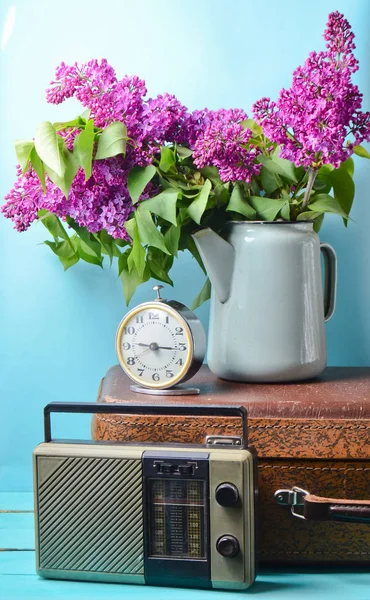 Leylak emaye çaydanlık antika bavul, vintage radyo, çalar saat mavi arka plan üzerinde buket. Retro tarzı hala lif