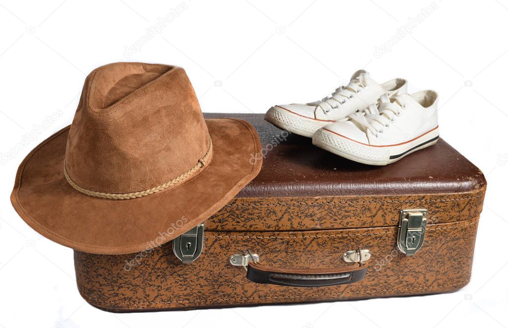 Old leather suitcase, retro sneakers, felt hat isolated on white background. The concept of trave