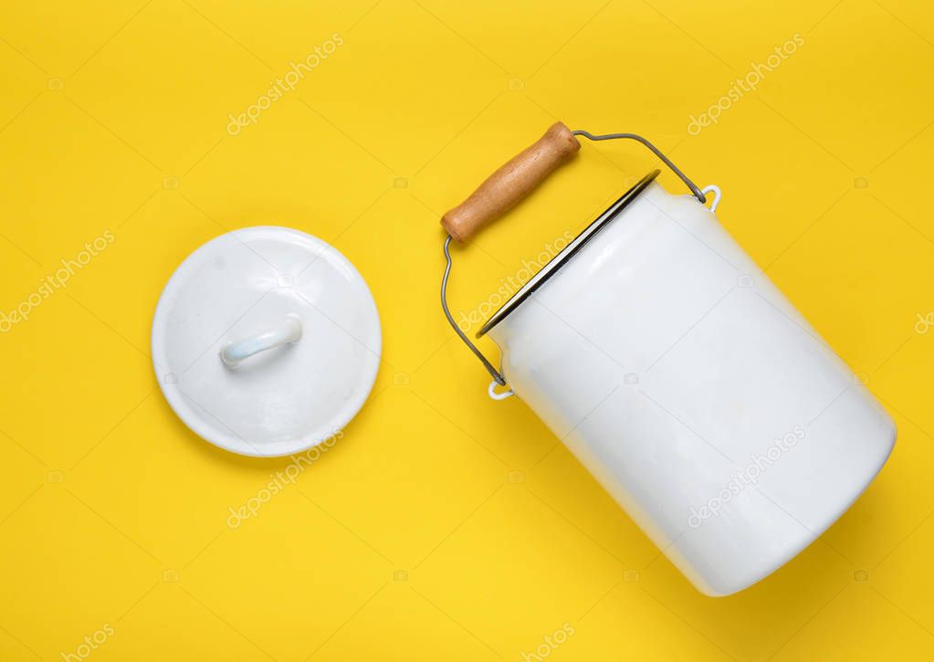 Enameled milk can on yellow pastel background. Top View