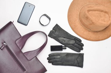 Kadın aksesuarları ve becerikli alet üstünde beyaz bir arka plan. Çanta, şapka, eldiven, smartphone, akıllı izlemek, parfüm şişesi. Sonbahar bahar koleksiyonu. Üstten görünüm. Düz yatıyordu