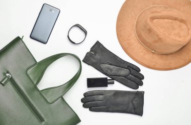 Kadın aksesuarları ve becerikli alet üstünde beyaz bir arka plan. Çanta, şapka, eldiven, smartphone, akıllı izlemek, parfüm şişesi. Sonbahar bahar koleksiyonu. Üstten görünüm. Düz yatıyordu
