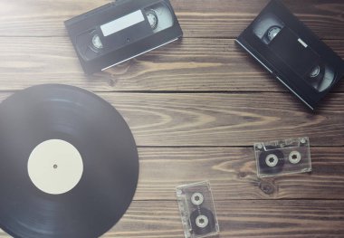 Vinil kayıt, video kaset, ahşap arka plan üzerinde ses kaset. Üstten görünüm. Retro medya teknoloji, kopya girintili