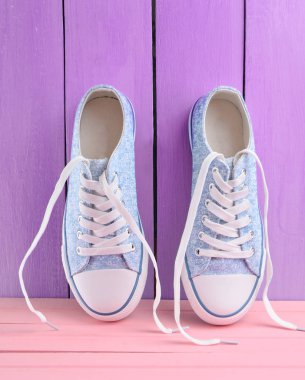 Bir mavi ahşap duvar arka plan, pastel renk tren pembe bir ahşap zemin üzerinde beyaz dantel ile kadın retro hipster spor ayakkabı
