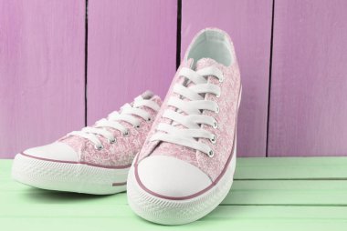 Bir mavi ahşap duvar arka plan, pastel renk tren pembe bir ahşap zemin üzerinde beyaz dantel ile kadın retro hipster spor ayakkabı
