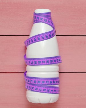 Bir cetvel üzerinde mavi bir ahşap masa, diyet, zayıflama kavramı yoğurt şişe sarılı, top vie