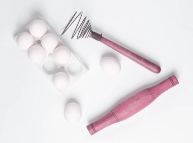 Pişirme işlemi. Çırpma teli beyaz bir arka plan üzerinde plastik tepsi ile beyaz yumurta, oklava. Üstten görünüm