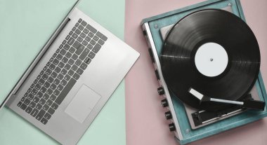 Dizüstü bilgisayar, pastel renkli bir arka plan üzerinde vinil oyuncu. Modern ve eski teknoloji, top vie