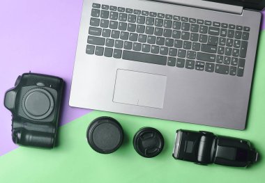 Ekipman fotoğrafçı, dizüstü bilgisayar, çanta dolar, pastel pembe mavi arka plan ile. Serbest kavramı, fotoğrafçının çalışmaları, nesneleri, üstten görünüm, düz la