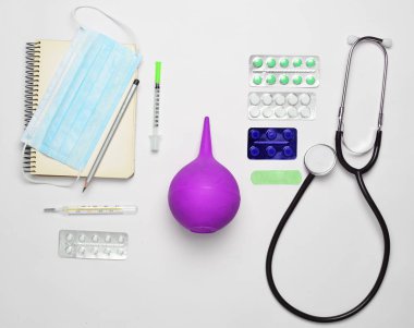 Beyaz bir arka plan üzerinde tıbbi malzeme. Stetoskop, tablet, termometre, defter, şırınga, lavman. Tıbbi kavramı, üstten görünüm, düz yatıyordu styl