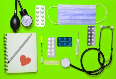 Sarı bir arka plan üzerinde tıbbi Kardiyoloji ekipmanları. Kabarcıklar hapları, defter, stetoskop, şırınga, termometre, manometre. Tıbbi kavramı, üstten görünüm, düz yatıyordu styl