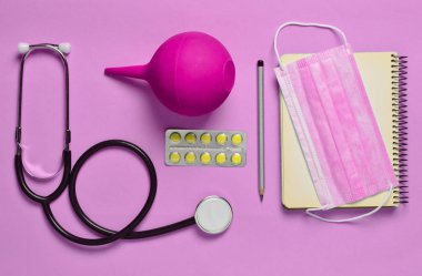 Tıbbi malzeme mavi bir arka plan üzerinde. Lavman, balon hapları, Not defteri, stetoskop, şırınga, termometre. Tıbbi kavramı, üstten görünüm, düz yatıyordu styl