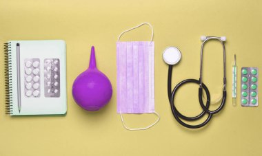 Tıbbi ekipman pembe bir arka plan üzerinde. Lavman, balon hapları, Not defteri, stetoskop, termometre. Tıbbi kavramı, üstten görünüm, düz yatıyordu stil, kopyalama alanı