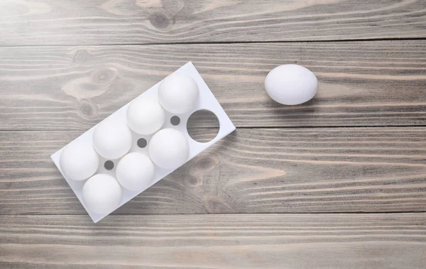 Plastic tray with white eggs on wooden table, minimalism trend, top vie