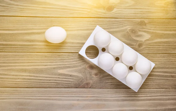 Plastic tray with white eggs on wooden table, minimalism trend, top vie