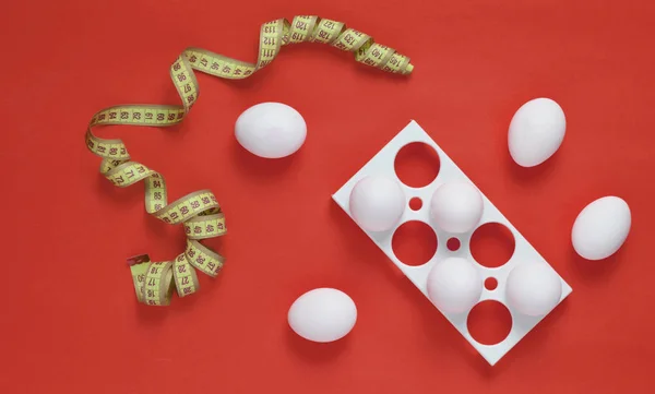 Plastic tray with white eggs and a ruler on a yellow pastel background, minimalism trend, top vie