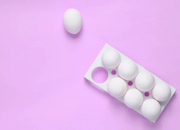 Plastic tray with white eggs on a pink pastel background, minimalism trend, top vie