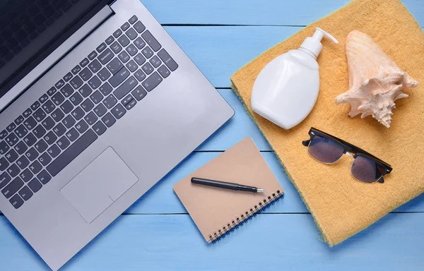 Online work at a beach resort. Laptop, towel, notepad, sunglasses, shell, sunblock, top view, flat la