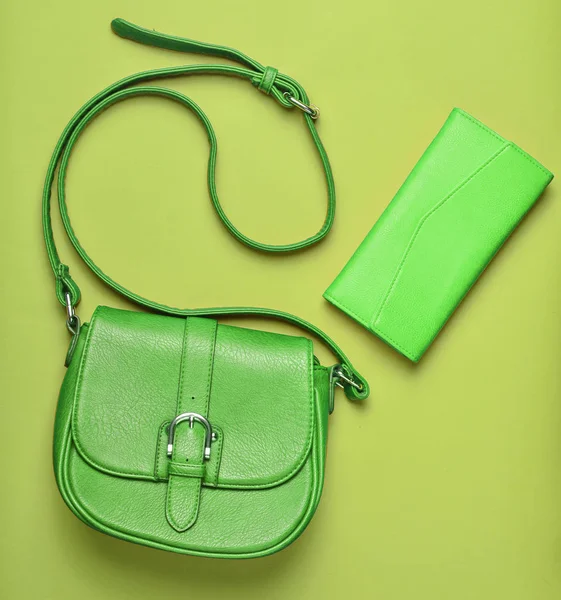 Women's leather red bag and purse on a green pastel background, women's accessories, top view, minimalis