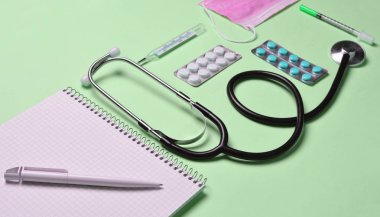 Tıbbi ekipman üzerinde bir pastel pembe. Kabarcıklar hapları, Not defteri, stetoskop, termometre. Tıbbi kavramı, üstten görünüm, düz yatıyordu styl