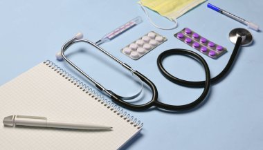 Tıbbi ekipman üzerinde bir pastel pembe. Kabarcıklar hapları, Not defteri, stetoskop, termometre. Tıbbi kavramı, üstten görünüm, düz yatıyordu styl