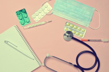 Tıbbi ekipman üzerinde bir pastel pembe. Kabarcıklar hapları, Not defteri, stetoskop, termometre. Tıbbi kavramı, üstten görünüm, düz yatıyordu styl