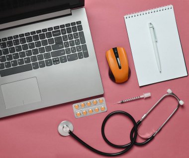 Çalışma alanı'nı modern bir doktor. Dizüstü bilgisayar, kablosuz fare, defter, stetoskop, hap, şırınga pastel mavi bir arka plan üzerinde. Üstten görünüm, minimalist tren