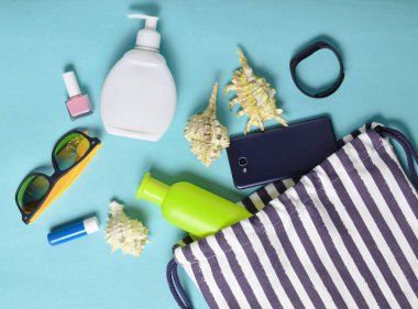 Plaj çantası ve aksesuarları pastel mavi arka plan üzerinde plaj düzendeki rahatlamak için. Deniz, yaz saati Resort'ta kavramı. Üstten görünüm, düz yatıyordu, minimalis