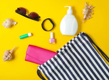 Plaj çantası ve plaj düzendeki sarı pastel arka plan üzerinde rahatlatıcı için aksesuarlar. Deniz, yaz saati Resort'ta kavramı. Üstten görünüm, düz yatıyordu, minimalis