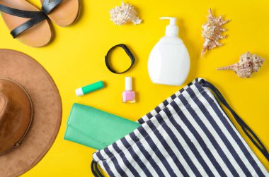 Plaj çantası ve plaj düzendeki sarı pastel arka plan üzerinde rahatlatıcı için aksesuarlar. Deniz, yaz saati Resort'ta kavramı. Üstten görünüm, düz yatıyordu, minimalis