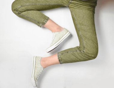 Kot pantolon ve spor ayakkabı beyaz bir arka plan üzerinde kadın bacaklar. Top Vie