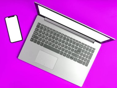 Laptop ve sarı bir arka plan üzerinde çerçevesiz telefon. Modern teknolojik araçlar, beyaz ekranları için kopya girintili