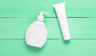 Mavi ahşap bir masa üzerinde krem beyaz plastik şişe, top vie