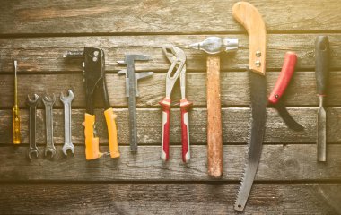 Ahşap bir masa üzerinde bir çalışma aracı. Testere, çekiç, tornavida, pense, dimes, bıçak, top vie