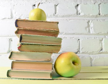 Eski kitaplar, beyaz tuğla duvar arka plan üzerinde elma yığını. Okul kavramı, eğitim