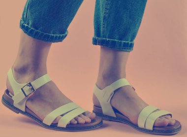 Kadın bacakları kot pantolon giymiş ve sandaletler bir pembe izole içinde ayakkabılı. Kadın moda. Kadın yaz footwea